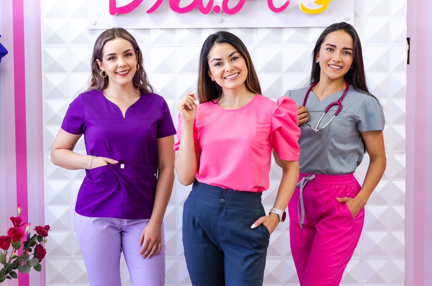 Tres mujeres del equipo de Dra. Li con uniformes morado, rosa y gris frente al logo de la marca